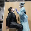 Nhân viên y tế lấy mẫu dịch xét nghiệm COVID-19 cho hành khách tại sân bay Narita, Nhật Bản. (Ảnh: AFP/TTXVN)