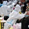 Nhân viên y tế lấy mẫu xét nghiệm COVID-19 cho người dân tại tỉnh Sơn Đông, Trung Quốc. (Ảnh: AFP/TTXVN)