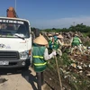 Công nhân Công ty Một thành viên Môi trường đô thị Hà Nội thu dọn rác thải bị đổ trộm tại Đại lộ Thăng Long. (Ảnh: Mạnh Khánh/TTXVN)