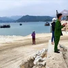 Lực lượng chức năng tại hiện trường khu vực nơi doanh nghiệp đổ trộm đất đá xuống vịnh Bái Tử Long. (Ảnh: TTXVN phát)