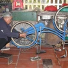 Ông Lê Trọng Kính sửa xe đạp cũ để tặng học sinh nghèo. (Ảnh: Thùy Dung/TTXVN)