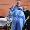 Nhân viên y tế chuyển bệnh nhân COVID-19 tới bệnh viện ở London, Anh. (Ảnh: AFP/TTXVN)