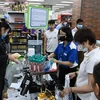 Người dân đeo khẩu trang phòng lây nhiễm COVID-19 khi mua hàng tại siêu thị ở Singapore. (Ảnh: AFP/TTXVN)