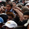 Người di cư Honduras phá hàng rào cảnh sát để vào Guatemala tìm đường tới Mỹ tại khu vực biên giới Corinto, Honduras. (Ảnh: AFP/TTXVN)
