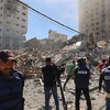 Các phóng viên tại hiện trường đổ nát của Toà tháp Jala, nơi đặt văn phòng một số hãng truyền thông quốc tế, sau khi máy bay Israel oanh tạc Dải Gaza, ngày 15/5. (Ảnh: AFP/TTXVN)