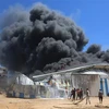 Lính cứu hỏa nỗ lực dập lửa căn nhà bị trúng oanh kích của máy bay Israel tại thành phố Rafah, Dải Gaza. (Ảnh: THX/TTXVN)