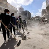 Các tình nguyện viên dọn dẹp đống đổ nát của các tòa nhà bị sập sau loạt không kích của Israel tại Dải Gaza. (Ảnh: AFP/TTXVN)