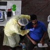 Nhân viên y tế lấy mẫu xét nghiệm COVID-19 cho công nhân tại Singapore. (Ảnh: AFP/TTXVN)
