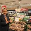 Đại sứ Việt Nam tại Nhật Bản Vũ Hồng Nam tự hào khi cầm trên tay vải thiều được bày bán tại siêu thị AEON. (Ảnh: Bùi Hà/TTXVN)