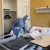 Nhân viên y tế chăm sóc bệnh nhân COVID-19. (Ảnh: AFP/TTXVN)