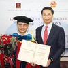 Tổng Lãnh sự Việt Nam tại Hong Kong Phạm Bình Đàm (phải) thay mặt Trường Đại học Hà Nội trao bằng Tiến sỹ danh dự cho ông Lâm Kiến Trung, Chủ tịch Tập đoàn Zhang Yang Group HoldingsLtd Hong Kong. (Ảnh: TTXVN)
