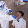 Bác sỹ lấy mẫu xét nghiệm cho một người dân Vientiane tại một điểm xét nghiệm dã chiến. (Ảnh: Phạm Kiên/TTXVN)