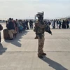 Binh sỹ đảm bảo an ninh khi người dân lên máy bay quân sự của Italy tại sân bay Kabul để sơ tán khỏi Afghanistan. (Ảnh: AFP/TTXVN)