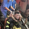 Lực lượng Cảnh sát Phòng cháy chữa cháy và cứu nạn cứu hộ đưa người bị nạn ra khỏi đám cháy. (Ảnh TTXVN phát)