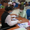 Chuyên viên Trung tâm Giải quyết thủ tục hành chính tỉnh Cà Mau hướng dẫn người dân cách thức giao dịch và kiểm tra ngay trên điện thoại di động. (Ảnh: Minh Hưng/TTXVN)