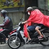 Người dân Hà Nội mặc áo mưa di chuyển trong cơn mưa sáng 11/8. (Ảnh: Thanh Tùng/TTXVN)