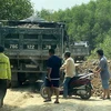 Một số đối tượng dùng xe tải chặn đầu, đổ đất bịt kín lối ra khỏi mỏ đất để uy hiếp phóng viên. (Ảnh: Lê Ngọc Phước/TTXVN)