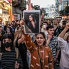 Một người biểu tình cầm bức chân dung của Mahsa Amini, một phụ nữ trẻ Iran đã chết sau khi bị cảnh sát bắt giữ ở Tehran. (Nguồn: AFP)