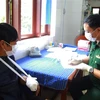 Cán bộ quân y thăm khám, kiểm tra sức khỏe cho bệnh nhân Mai Văn Miên (bên trái). (Ảnh: TTXVN phát)