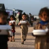 Trẻ em Syria nhận thức ăn cứu trợ tại trại tị nạn ở Dana, tỉnh Idlib. (Ảnh: AFP/TTXVN)