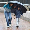 Người dân di chuyển dưới trời mưa to gió lớn do ảnh hưởng của bão Koinu tại Hong Kong, Trung Quốc. (Ảnh: AFP/TTXVN)