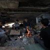 Người dân Palestine nhóm lửa sưởi ấm trong những căn nhà bị phá hủy bởi xung đột tại thành phố Khan Younis, Dải Gaza. (Ảnh: THX/TTXVN)