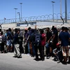 Người di cư chờ xét duyệt bên ngoài Cơ quan kiểm soát biên phòng Mỹ, sau khi vượt qua biên giới Mexico vào El Paso, bang Texas (Mỹ). (Ảnh: AFP/TTXVN)