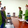 Lực lượng chức năng đọc lệnh khởi tố và bắt tạm giam Trần Quang Anh. (Ảnh: TTXVN phát)