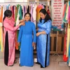 Cán bộ Hội Liên hiệp Phụ nữ huyện Vũng Liêm, tỉnh Vĩnh Long giúp hội viên lựa chọn chiếc áo dài phù hợp. (Ảnh: Lê Thúy Hằng/TTXVN)
