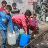 Trẻ em lấy nước tại vòi nước công cộng ở thành phố Rafah, Dải Gaza. (Ảnh: AFP/TTXVN)