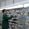 Anh Minh Đức đang sắp xếp lại hàng hóa trên kệ ở cửa hàng tiện lợi 24/24 Seven-Eleven. (Ảnh: Xuân Giao/TTXVN)
