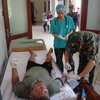 Lực lượng quân y đang kiểm tra sức khỏe của ngư dân Sáu khi vừa tiếp nhận. (Ảnh: TTXVN phát)
