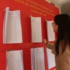 Người dân xem thông báo niêm yết danh sách cử tri, lấy ý kiến việc sắp xếp đơn vị hành chính cấp phường, trên địa bàn phường Cầu Dền, Hà Nội. (Ảnh: Nguyễn Thắng/TTXVN)