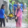 Đoàn thanh niên giúp dân dọn dẹp đồ đạc khắc phục hậu quả mưa lụt. (Ảnh: Nguyễn Hoàng/TTXVN)