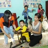 Các tình nguyện viên người Hàn Quốc phục hồi chức năng cho trẻ em khuyết tật. (Ảnh: Hồ Cầu/TTXVN)