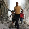 Người dân Syria sơ tán khỏi khu vực đổ nát sau một cuộc không kích ở Aleppo ngày 22/4 vừa qua. (Ảnh: AFP/TTXVN)