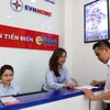 Đoàn thanh niên EVN HCMC hướng dẫn khách hàng thanh toán tiền điện không dùng tiền mặt và các dịch vụ về điện. (Ảnh: Thanh Vũ/TTXVN)