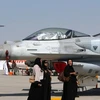 Phụ nữ đi ngang qua chiếc máy bay chiến đấu F-16 do Mỹ chế tạo được trưng bày tại Dubai Airshow. (Nguồn: AFP)