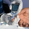Nhân viên y tế lấy mẫu máu để thử đường huyết cho một bệnh nhân. (Ảnh: AFP/TTXVN)
