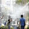 Người dân giải nhiệt tại các vòi phun nước ở Tokyo. (Nguồn: Kyodo/TTXVN)
