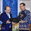 Tổng thống nước Cộng hòa Indonesia Joko Widodo tặng ảnh lưu niệm cho Thủ tướng Nguyễn Xuân Phúc tại cuộc gặp gỡ báo chí sau hội đàm. (Ảnh: Thống Nhất/TTXVN)