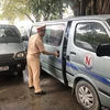 Cảnh sát giao thông kiểm tra một xe ôtô chở học sinh bị tạm giữ. (Ảnh: Đức Phương/TTXVN)