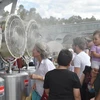 Người dân tránh nóng bằng quạt hơi nước tại Sydney. (Ảnh: AFP/TTXVN)