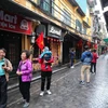Khách du lịch quốc tế trải nghiệm không khí sáng mùng 1 Tết tại phố Tạ Hiện. (Ảnh: Thành Đạt/TTXVN)