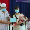 Phó Giám đốc Bệnh viện Bệnh Nhiệt đới Khánh Hòa Nguyễn Vũ Quốc Bình tặng hoa và trao giấy xuất viện cho bệnh nhân Lê Thị Thu H. (Ảnh: Phan Sáu/TTXVN)