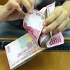 Một nhân viên đếm tiền giấy rupiah của Indonesia. (Nguồn: thestar)