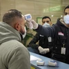 Nhân viên Cơ quan kiểm dịch Ai Cập kiểm tra thân nhiệt hành khách nhằm ngăn ngừa dịch viêm đường hô hấp cấp COVID-19 tại sân bay quốc tế Cairo. (Ảnh: AFP/TTXVN)