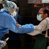 Y tá giúp đỡ một bệnh nhân lớn tuổi tới khám bệnh tại Tegucigalpa, Honduras, ngày 1/4 vừa qua. (Ảnh: AFP/TTXVN)