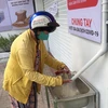 Một người phụ nữ bán vé số nhận gạo. (Ảnh minh họa: Hứa Chung/TTXVN)