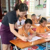 Giáo viên Tiểu học hướng dẫn học sinh làm bài tập. (Ảnh: Nguyễn Lành/TTXVN)